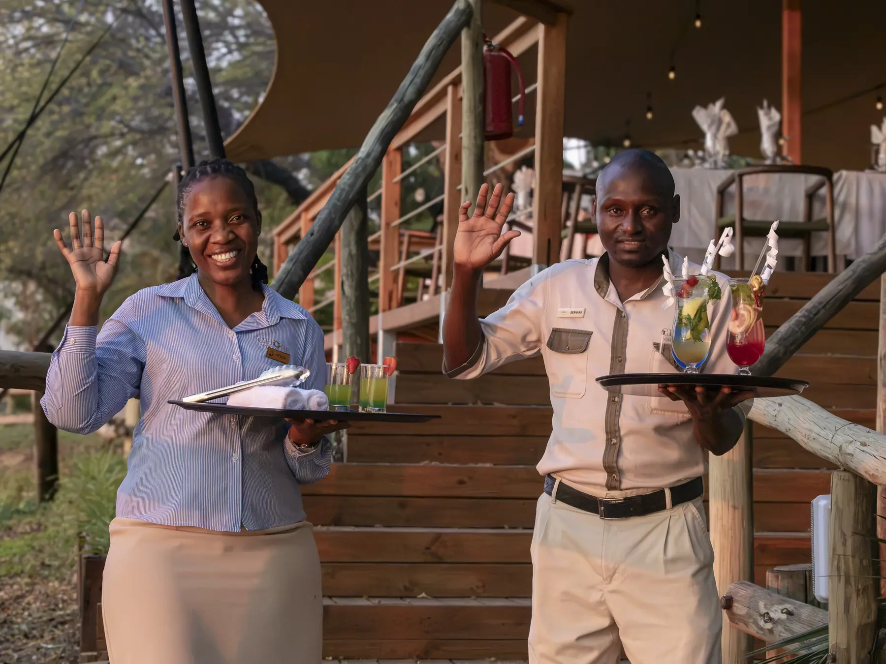 Two of the lodge team waving a welcome on the deck steps